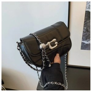 Detail of a black quilted leather chain bag with a silver metallic ball clasp