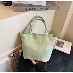 Dettaglio della borsa tote in nylon verde chiaro con etichetta centrale e doppi manici
