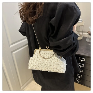 Detail of white lace handbag with faux pearls, gold metal clasp and chain strap