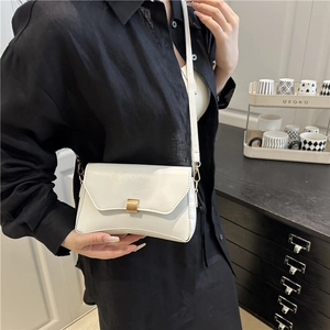 Borsa a tracolla bianca minimalista con chiusura dorata indossata da una modella