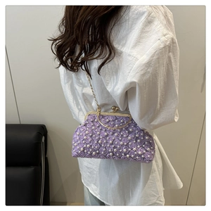 Detail of a purple floral lace evening bag with 3D flowers and pearls on a metal chain
