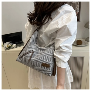 Detail of herringbone tote bag with brown leather trim and diagonal zipper pocket