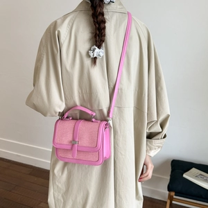 Pink PU leather and woven texture crossbody bag with metal buckle on beige trench coat
