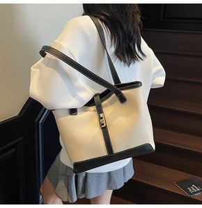 Detail of a large cream tote bag with black trim and white contrast stitching details