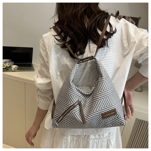 Detail of grey herringbone fabric bag with brown leather accents and fashion tag