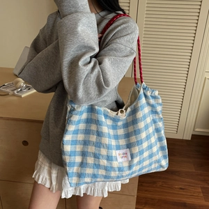 Blue checkerboard tote bag with red rope handles in a stylish minimalist interior setting