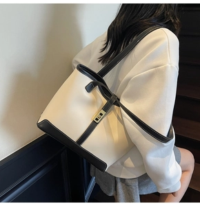 Detail view of large tote bag with cream leather and black trim on a fashion model
