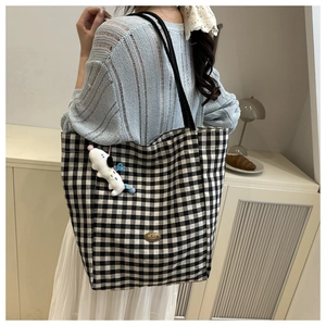 Detail of checkered canvas tote bag with metal handmade tag and cute plush puppy charm
