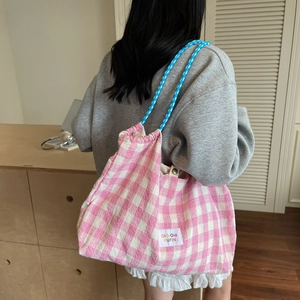 Pink checkered drawstring shoulder bag with colorful rope handles in a lifestyle setting