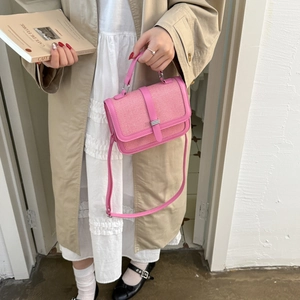 Pink textured woven crossbody bag with top handle and stylish vertical buckle detail
