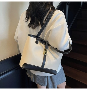 Detail of a large tote bag with contrast stitching and a gold rectangular metal lock