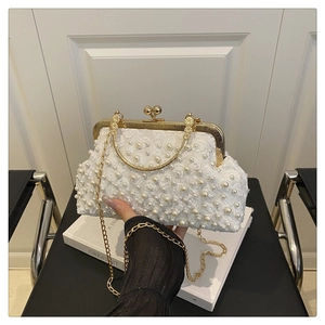 Close-up of white lace evening clutch bag featuring pearl embellishments and gold kiss-lock