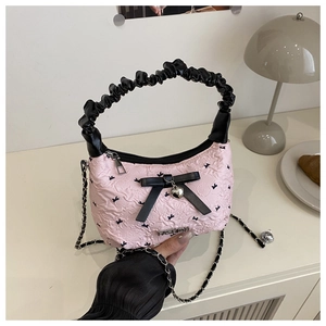 Detail of pink bubble texture handbag with black silk bows and heart charm