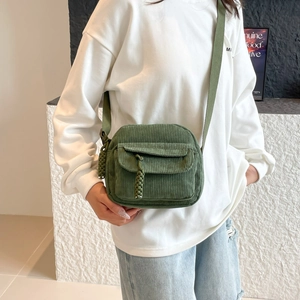 Green corduroy crossbody bag with front pocket and braided rope detail on a white hoodie