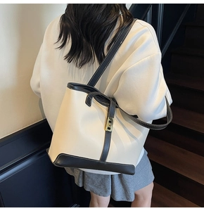 Detail of cream tote bag with dark coffee trim and gold swivel clasp on model