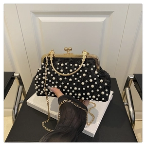 Detail of black floral lace evening bag with white pearls and gold metal handle