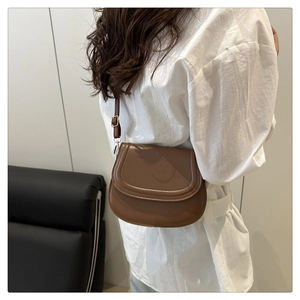 Brown saddle shoulder bag shown on model featuring adjustable strap and matte finish