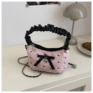Detailed shot of pink floral handbag with black bow and heart pendant on a desktop