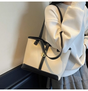 Detailed view of cream and black contrast tote bag with elegant gold metal buckle detail