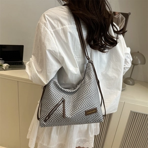 Minimalist herringbone tote bag with brown leather straps shown on a model in a modern office