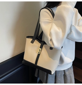Detail view of large cream and black tote bag with gold metal clasp on a model