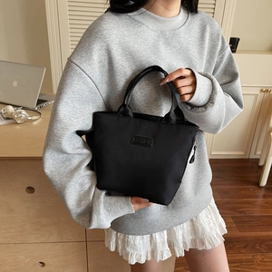 Minimalist black nylon bucket handbag with Fashion label and fabric handles
