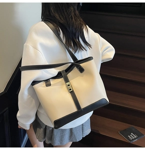 Fashionable beige tote bag with black trim and gold lock shown on model indoors