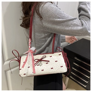 Detail of white underarm bag featuring red polka dots and a large lace bow accessory