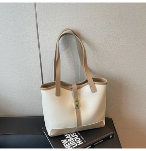 Detail of minimalist cream tote bag with brown straps and gold buckle on books