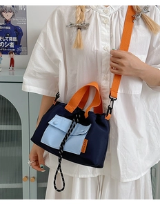 Close-up of contrast nylon crossbody bag showing orange strap and side brand label