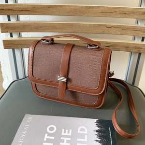Detail view of a brown vintage canvas handbag with leather trim and silver metal accent