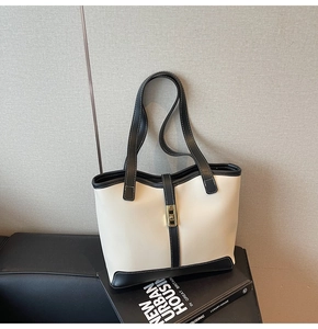 Close-up of minimalist bicolor tote bag with golden metal twist lock on urban books