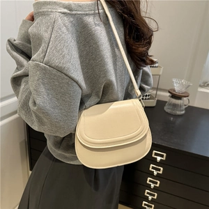 Fashionable beige leather saddle shoulder bag for women shown in a casual lifestyle setting