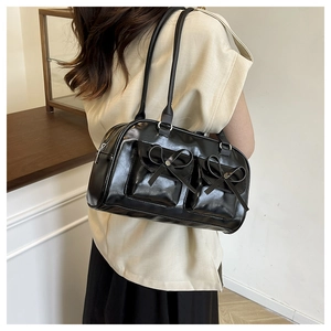 Close-up of black patent leather Boston bag with decorative satin bows and dual pockets
