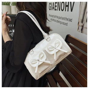 Detail of white leather shoulder bag with bow pockets and silver studs in outdoor setting