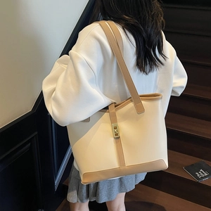 Chic beige and brown leather tote bag with gold lock for women on a stylish staircase