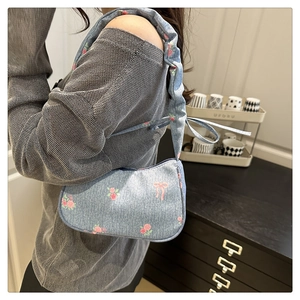Blue denim underarm bag with pink rose and bow prints featuring a scrunchie strap