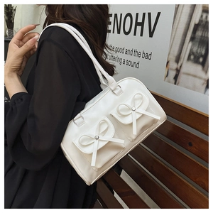 Detail of cream Boston bag featuring dual front pockets with decorative leather bows