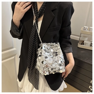 Close-up of silver sequin bucket bag with drawstring closure and chain strap on model