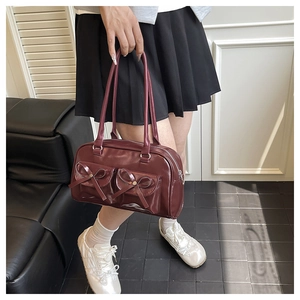 Detail of dark red vintage PU leather Boston bag with decorative bows and twin pockets