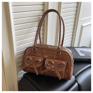 Close-up of vintage brown leather handbag featuring dual front pockets and bow accents