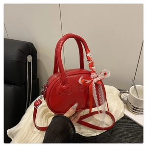 Detail of red patent leather bowling bag with bow accent and adjustable strap