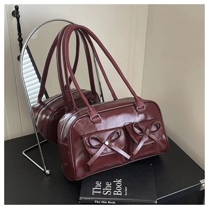 Detail of burgundy glossy PU shoulder bag with dual bow pockets and chic mirror reflection