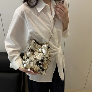 Fashionable gold sequin bucket bag with metal chain strap shown on a white shirt model
