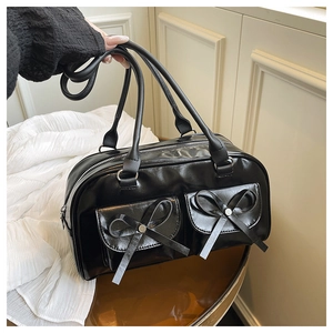 Detailed view of black patent leather Boston bag with bow accents and double pockets