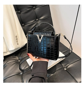 Detail of black crocodile texture handbag with silver V buckle and stylish hand carry handle