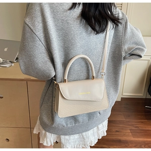 Detail view of beige square bag featuring woven texture and fashion bags text logo