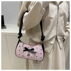 Détail du sac baguette rose gaufré avec nœud noir et pendentif coeur en métal