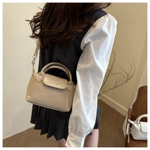 Dettaglio della piccola borsa quadrata beige chiaro con manico e tracolla sottile