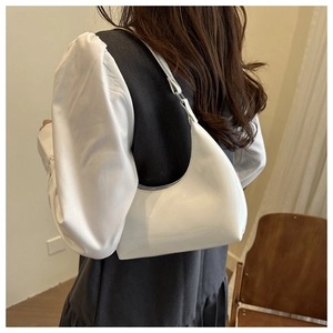 Dettaglio della borsa hobo in vernice bianca con finitura lucida sulla modella
